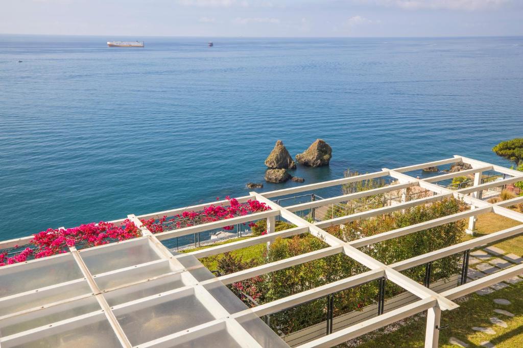 a white fence next to the water with flowers at casa Ferrigno in Vietri sul Mare
