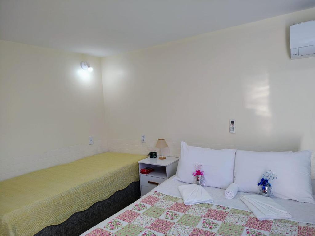 a white bedroom with a bed and a yellow blanket at Aconchego da Vovó in Araruama
