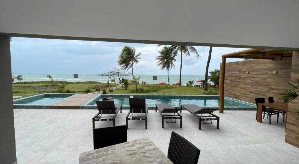 a patio with a table and chairs and a pool at Flat Carneiros Tamandaré Kauai beach in Tamandaré