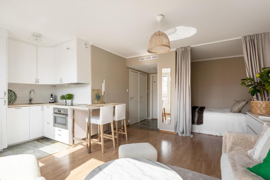 a kitchen and living room with white cabinets and a bed at Stylish Studio Apartment - Center in Stockholm