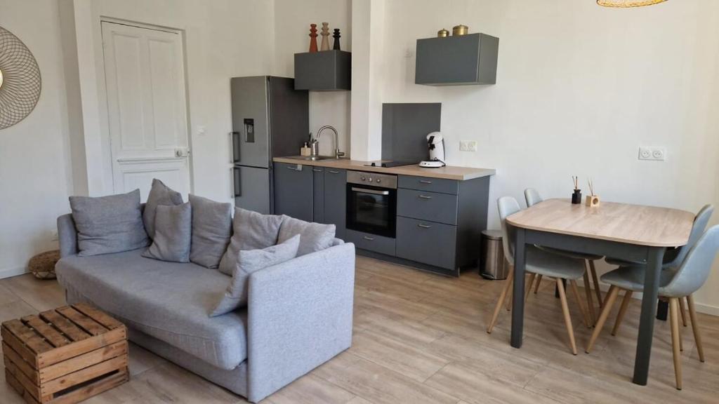un salon avec un canapé et une table et une cuisine dans l'établissement T2 calme à 11 minutes des Remparts - Wifi Parking, à Avignon