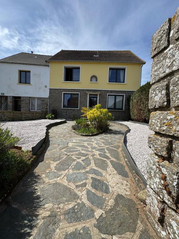 une maison avec une passerelle en pierre devant elle dans l'établissement la maison des souvenirs précieux, à Surtainville