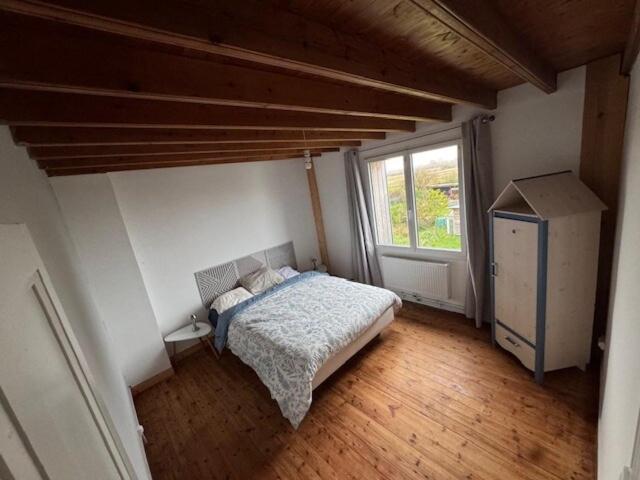 a bedroom with a bed and a window at la maison des souvenirs précieux in Surtainville