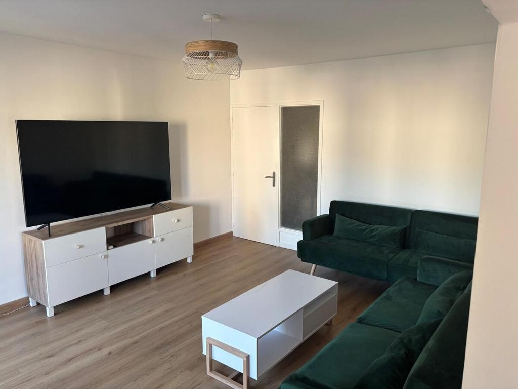 un salon avec un canapé vert et une télévision à écran plat dans l'établissement Logement calme et spacieux, à Marseille