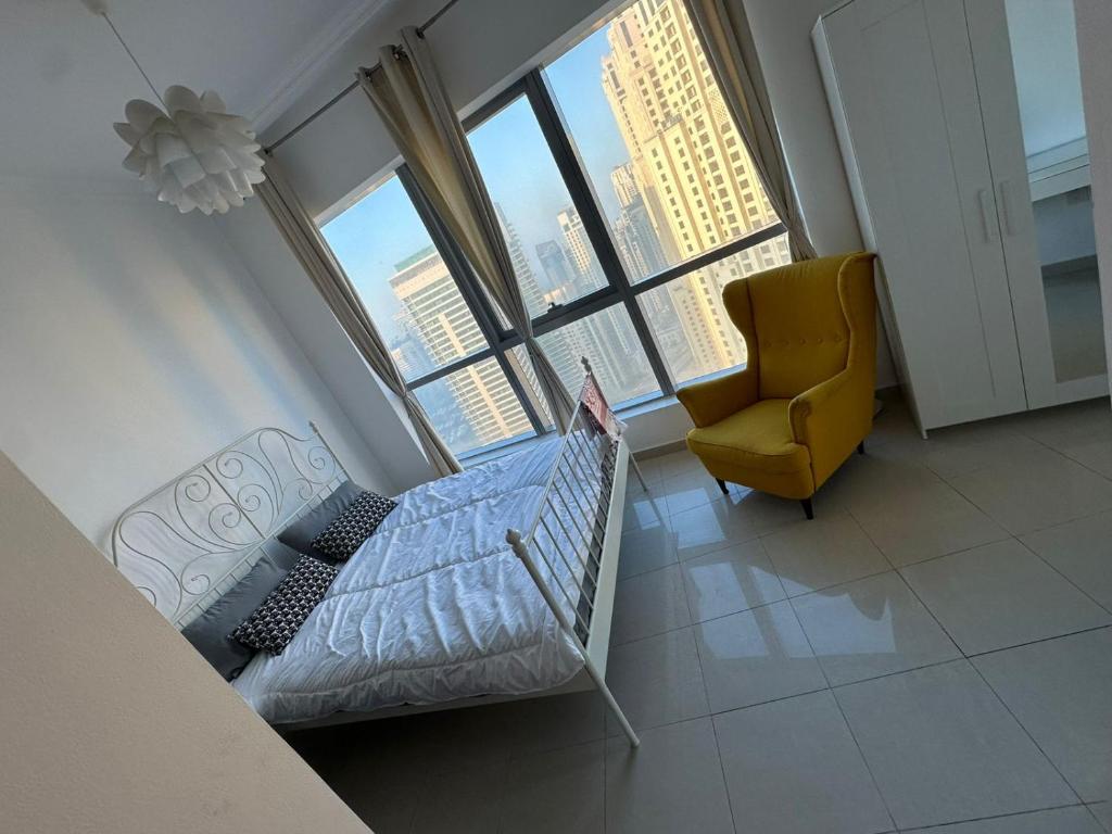 ein Schlafzimmer mit einem Bett und einem Stuhl und Fenstern in der Unterkunft Happy homes in Sabkhah