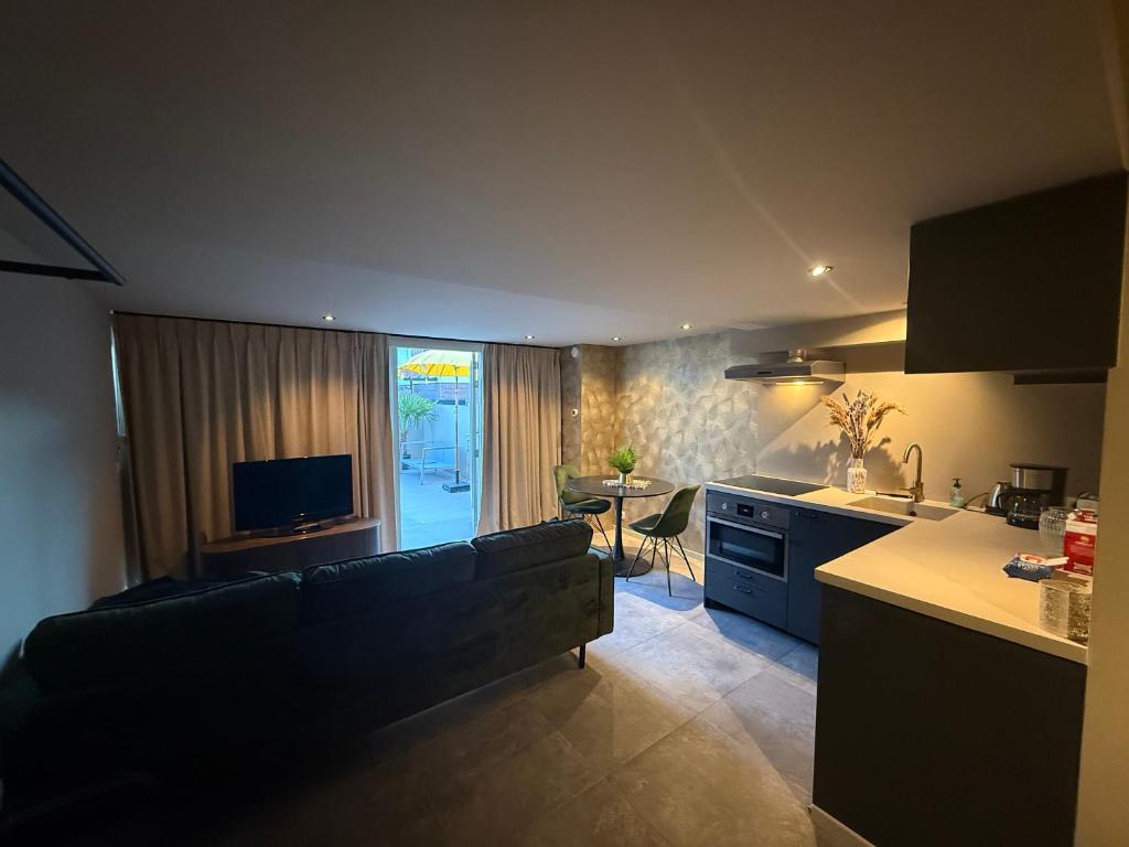 a kitchen and a living room with a couch and a table at Katwijks geluk in Katwijk aan Zee