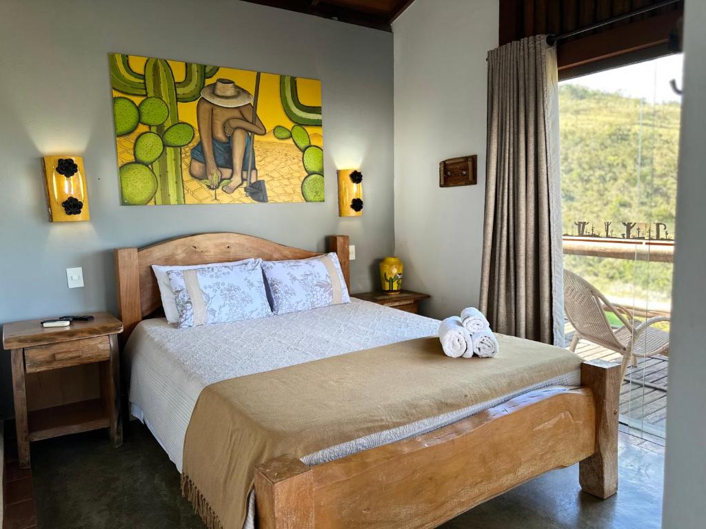Un dormitorio con una cama y un cuadro en la pared. en Pousada Fecho da Serra, en Capitólio