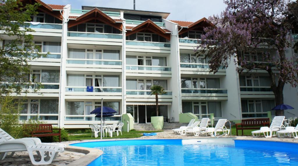a hotel with a pool and chairs and a building at Holiday Club Füred in Balatonfüred