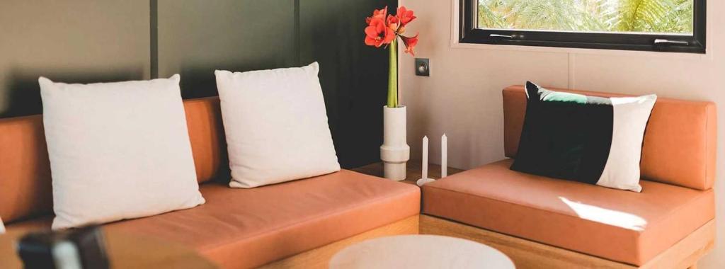 - deux canapés orange avec des oreillers et un vase avec une fleur rouge dans l'établissement Camping 4 étoiles - Piscine - efcha0, à Bourgneuf-en-Retz