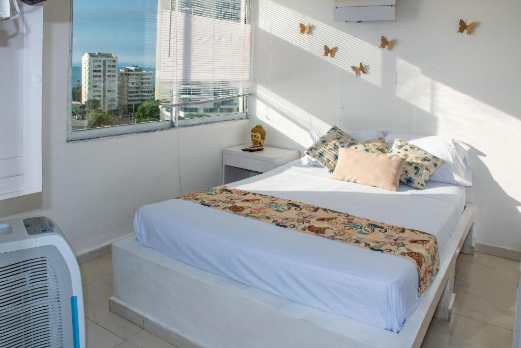 a white bedroom with a bed and a window at Ocean view - 77Rentals in Cartagena de Indias