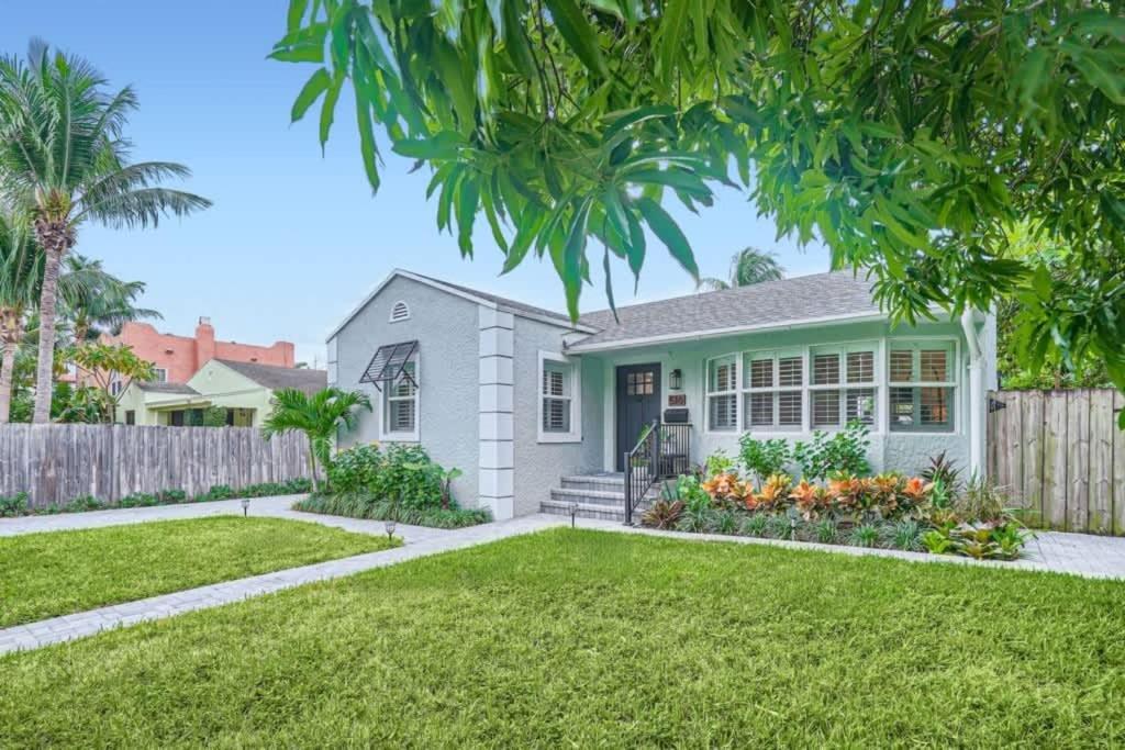 een grijs huis met een hek en een tuin bij Northwood Haven - Light-Filled Bungalow Close to Rybovich Marina in West Palm Beach