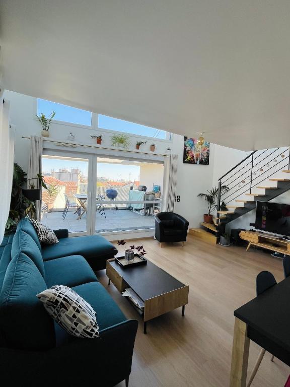 un salon avec un canapé bleu et une table dans l'établissement Magnifique duplex avec terrasse, à Romainville