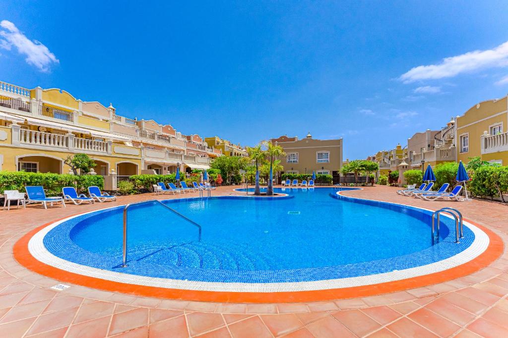 a swimming pool in a courtyard with chairs and condos at Oceanview Duplex, AC, Heated pool in Palm-Mar