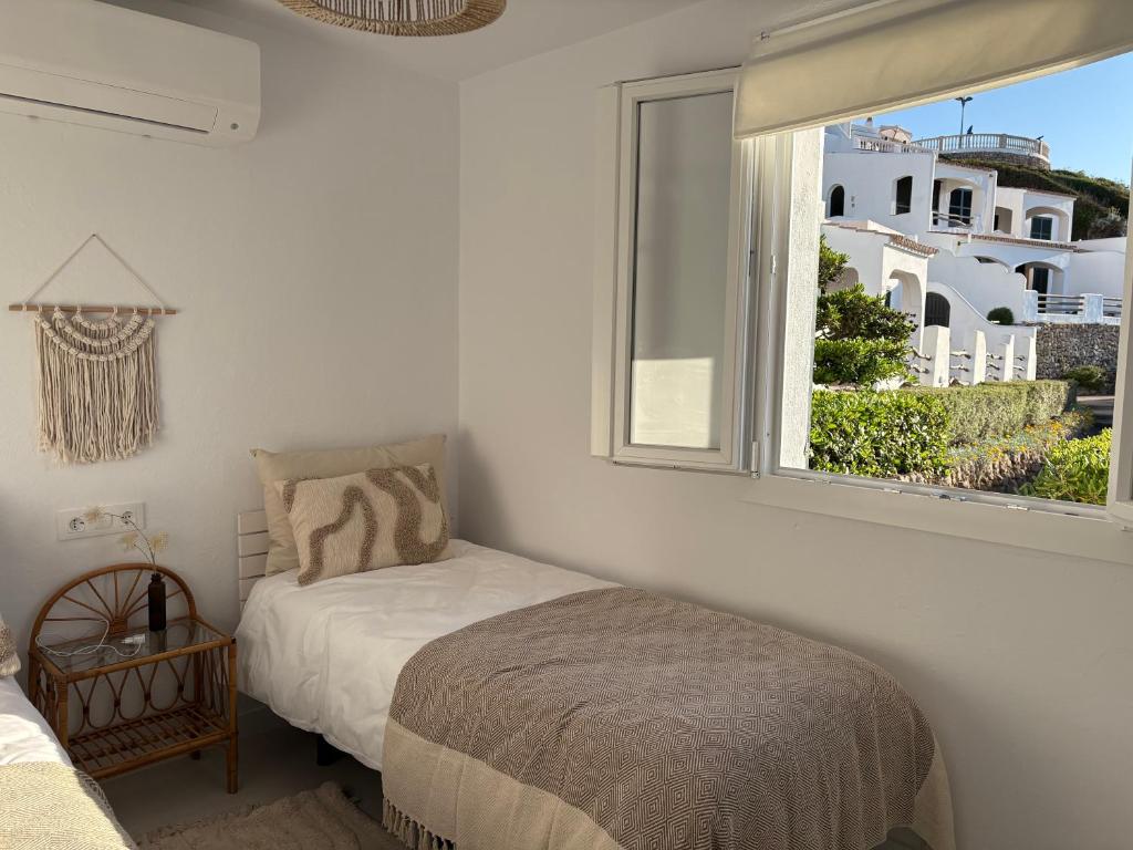 a small bedroom with a bed and a window at El Mirador de NaLi - accès direct à la plage in Arenal d'en Castell