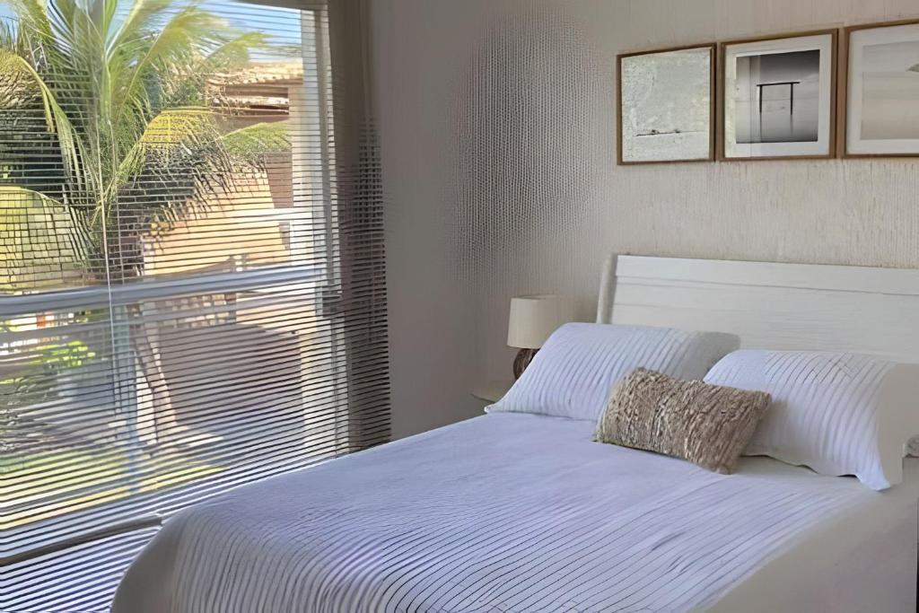 um quarto com uma cama com uma janela grande em Agradável Casa em Cond de frente para a Praia Rasa em Armacao dos Buzios