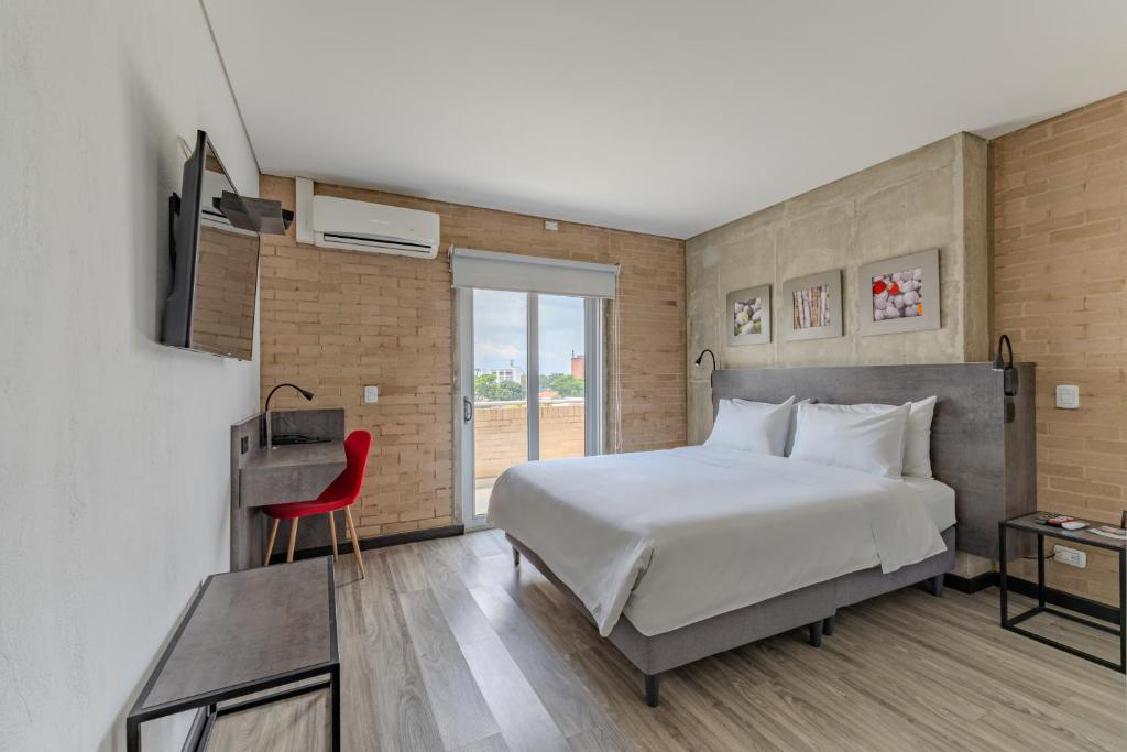 a bedroom with a large bed and a red chair at Hotel Quinta Norte Chipichape in Cali