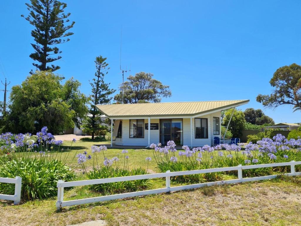 a small white house with a white fence and purple flowers at Catalina Cottage in Port Moonta