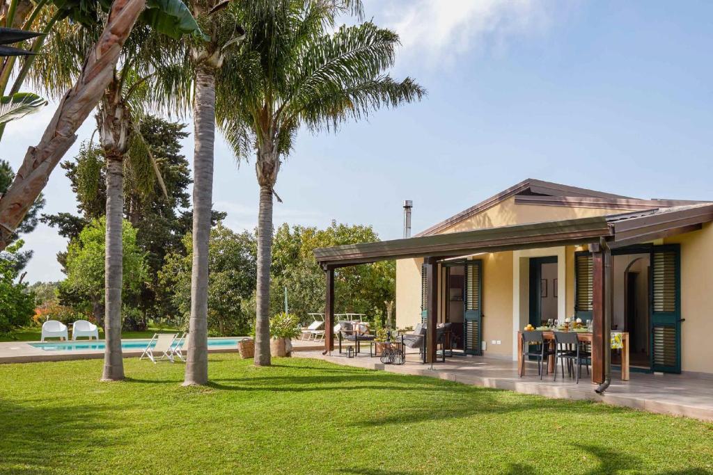 une maison avec une piscine et des palmiers dans l'établissement hiresicily - Giardino di Limoni, à Noto Marina