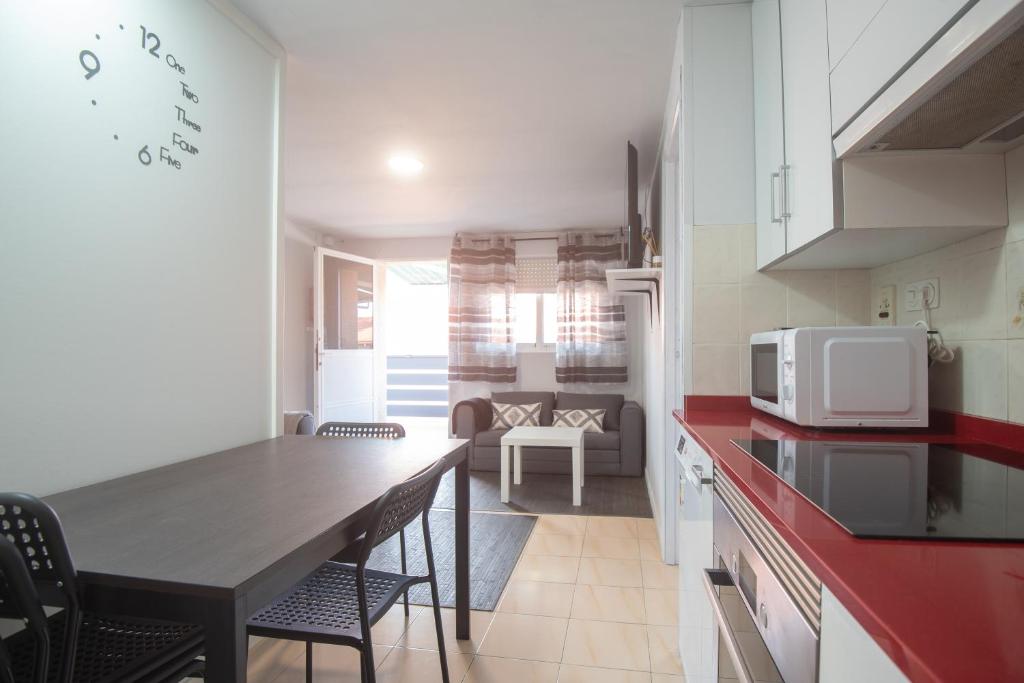 eine Küche mit einem Tisch mit Stühlen und einer Mikrowelle in der Unterkunft Solpor de Pedras Negras in San Vicente do Mar