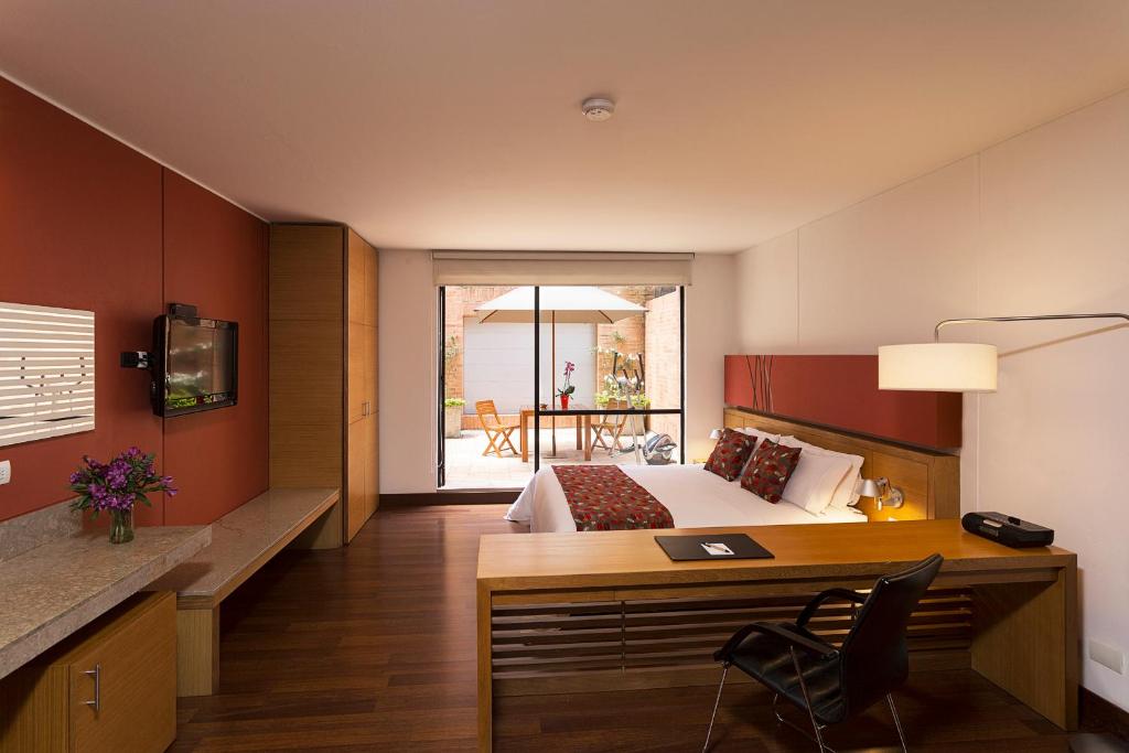 ボゴタにあるHotel bh La Quintaのベッド、デスク、デスクが備わるホテルルームです。