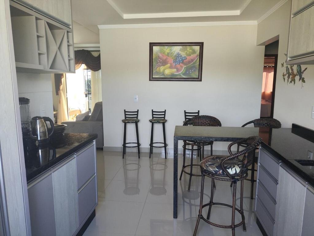 una cocina con mesa y taburetes. en Lar Radaelli, en Foz do Iguaçu