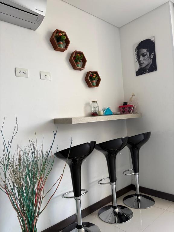 a white wall with a bar with black stools at Lindo Apartaestudio in Ricaurte