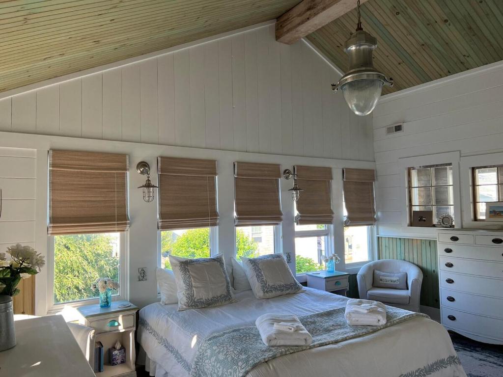 a bedroom with a bed with windows and a chair at Beach Haven Belle -OI Collection in Beach Haven