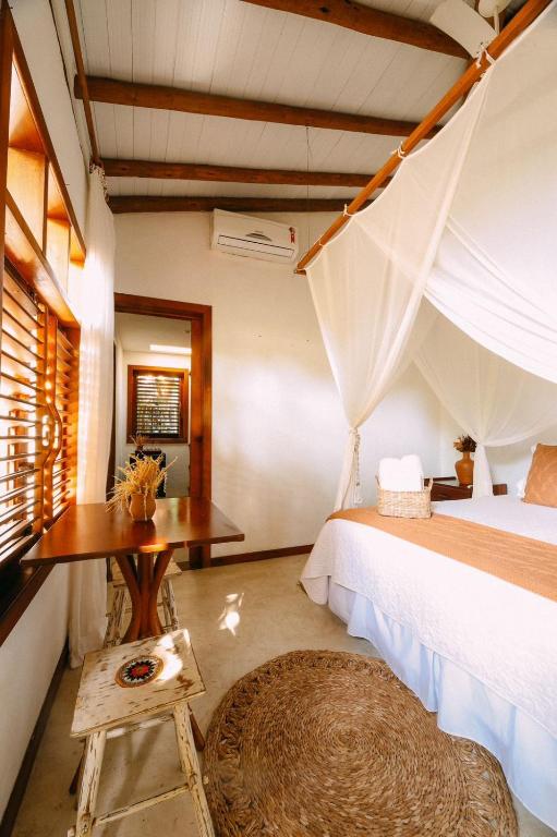 a bedroom with a bed and a desk and a table at Pousada Ó Paí, Ó in Caraíva