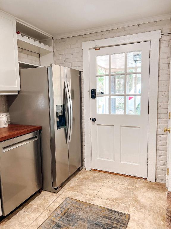 a kitchen with a refrigerator and a white door at Captains Courtyard - Heart of Historic Downtown Wilmington - 48 Firepit - Turf Yard in Wilmington
