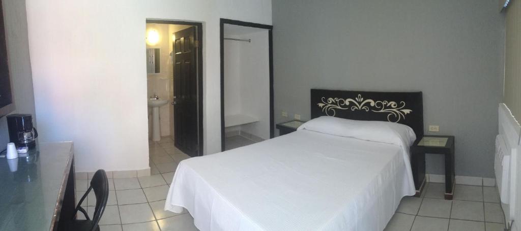 1 dormitorio con cama blanca y baño en Hotel Jardin en Heroica Caborca