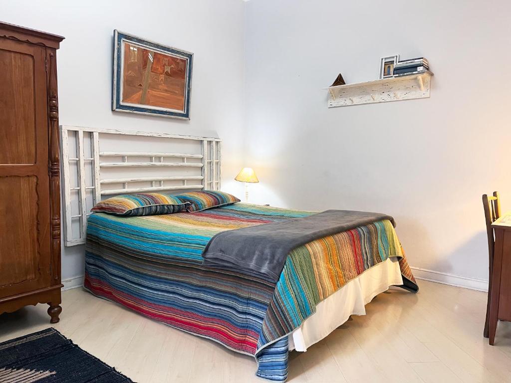 a bedroom with a bed with a colorful blanket on it at Suíte Exclusiva Charmosa com Varanda Verde - 100m da Paulista in Sao Paulo