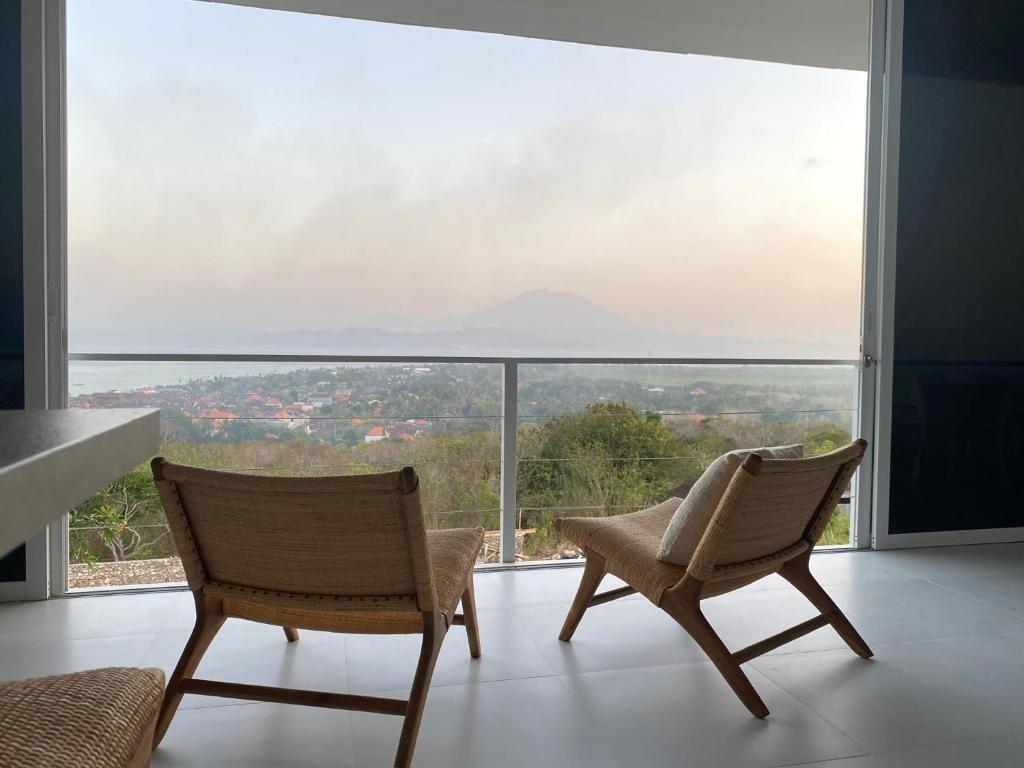 due sedie sedute in una stanza con una grande finestra di The Blue Zone Villa a Nusa Lembongan