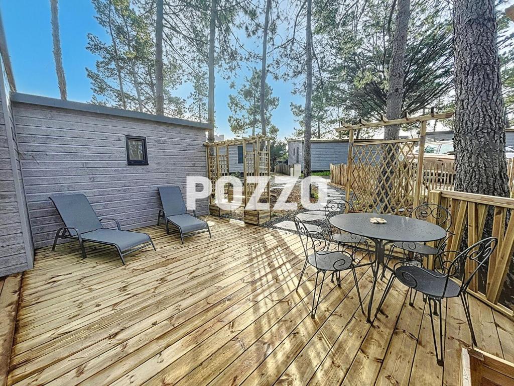 une terrasse en bois avec des chaises et une table. dans l'établissement Chalet de standing à Jullouville - 6 couchages - FR-1-361-568, à Jullouville