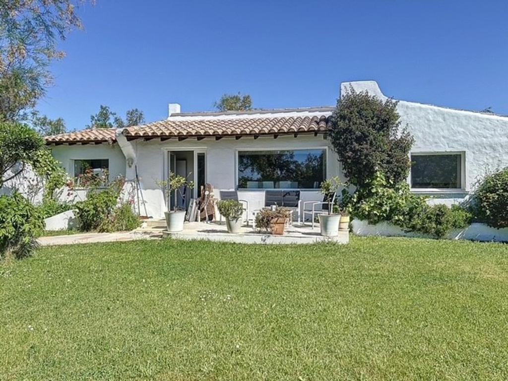 une maison blanche avec une pelouse devant dans l'établissement Mas authentique pour 8 personnes, piscine et jardin fleuri - FR-1-475-229, à Saintes-Maries-de-la-Mer