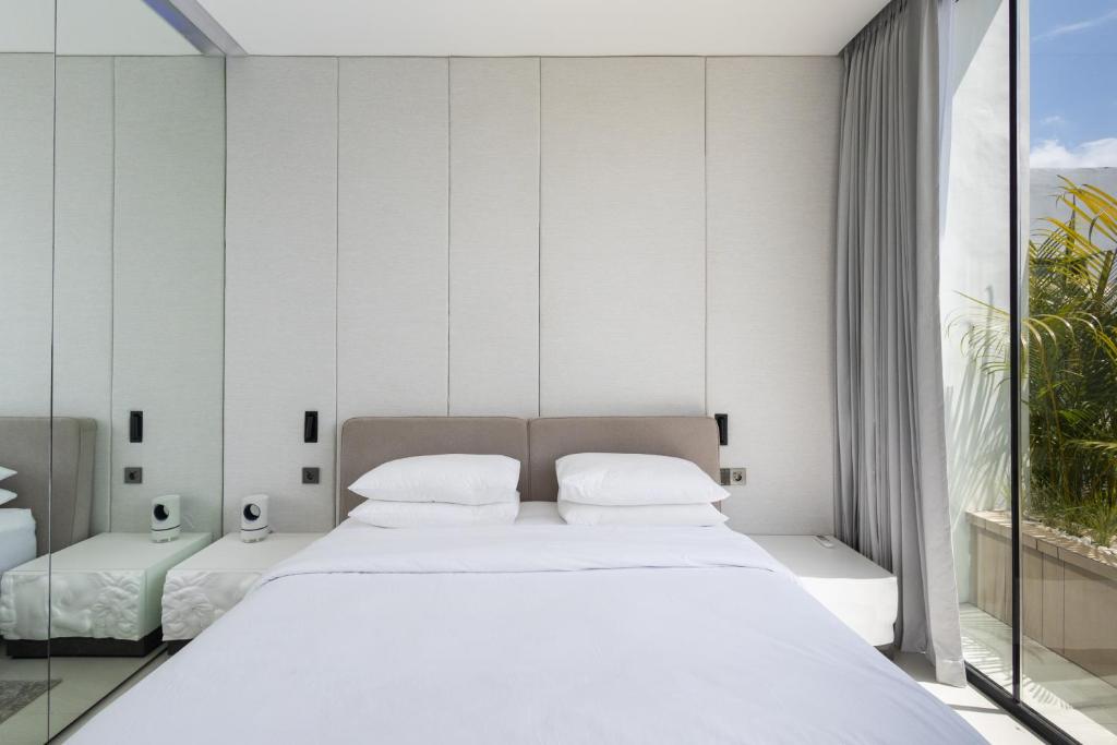 a bedroom with a large white bed and a window at Archestet Villas Canggu in Canggu