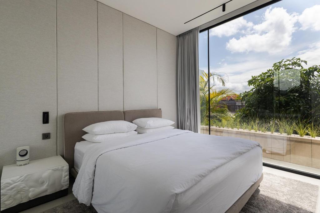 a bedroom with a white bed and a large window at Archestet Villas Canggu in Canggu