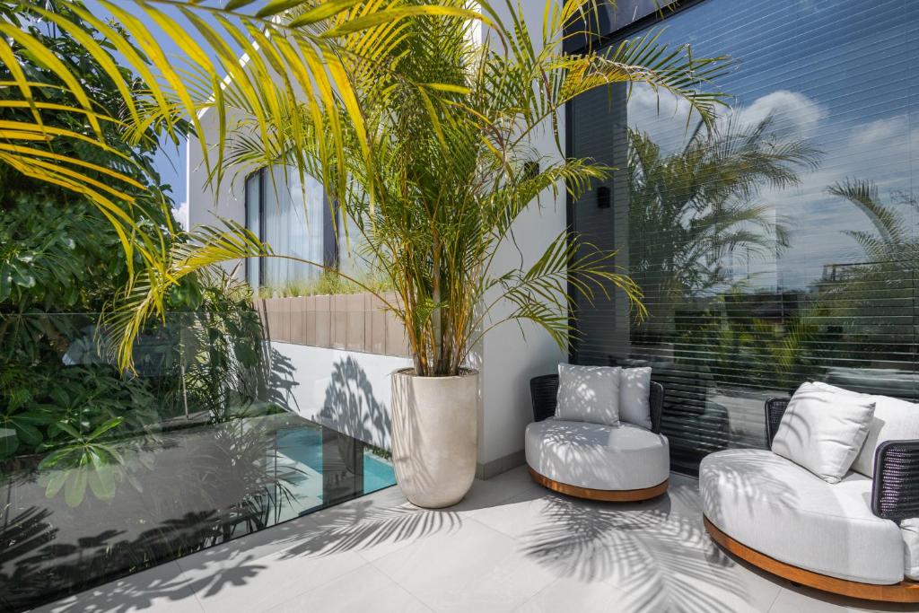 a patio with two white chairs and a potted plant at Archestet Villas Canggu in Canggu