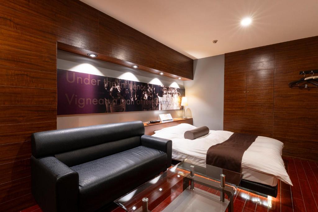 a hotel room with a bed and a couch at Asahikawa Hotel COLOR'S-Adult Only in Asahikawa