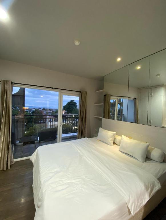 a bedroom with a large white bed with a large window at Lee Ardhin by Anggara in Seturan