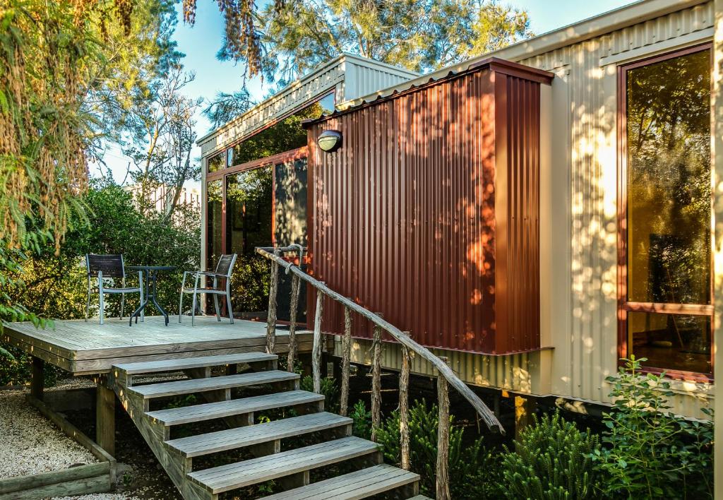 a tiny house with stairs leading to a deck at Misty River Retreat in Blenheim