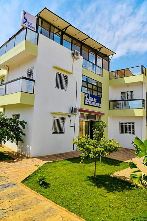 a white building with a tree in front of it at RELAX RESIDENCES Aéroport AIBD in Toulé