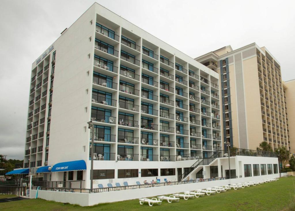 a large white hotel with white chairs in front of it at Holiday Sands South in Myrtle Beach