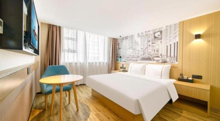 ein Hotelzimmer mit einem großen weißen Bett und einem Tisch in der Unterkunft City Comfort Inn Kunshan High-speed Railway Station Renmin Road in Kunshan