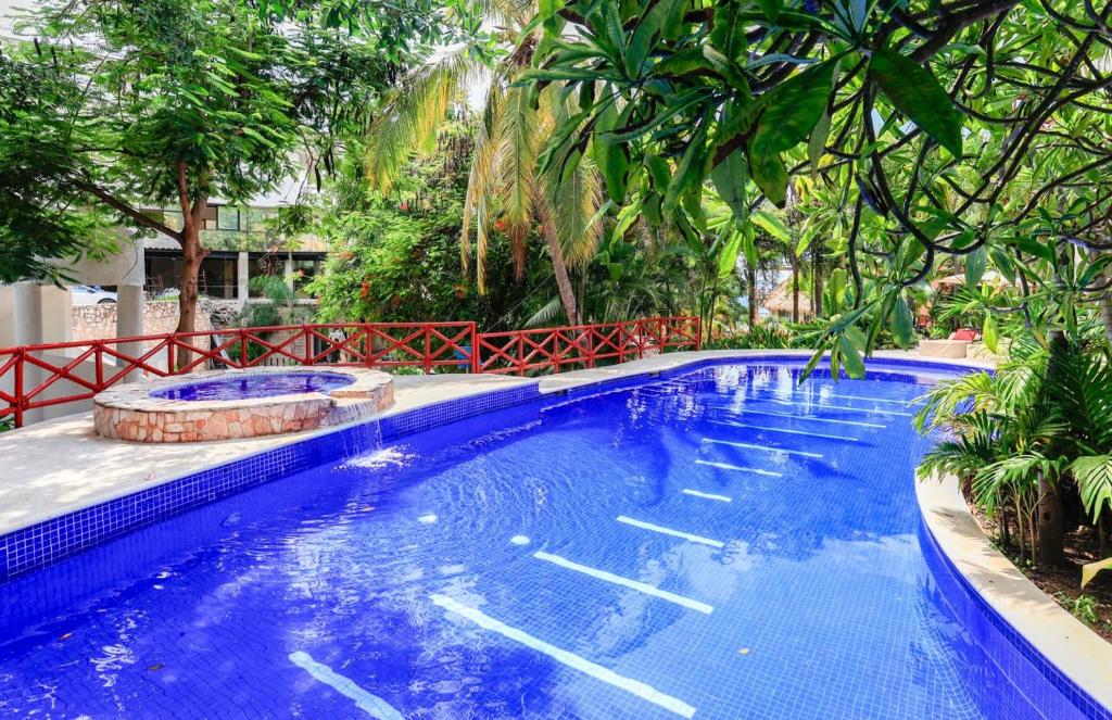 a large blue swimming pool with trees in the background at #703 Pajaro de Fuego in Sayulita