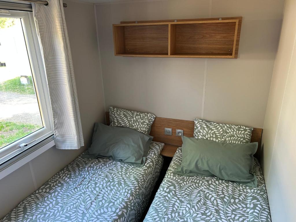 une petite chambre avec deux lits et une fenêtre dans l'établissement Mobilhome Mimizan Plage, à Mimizan