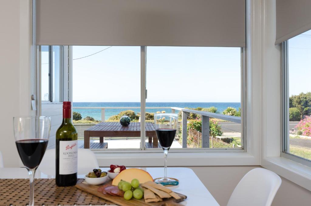 a table with two glasses of wine and a plate of food at Penguin Beach House in Penguin