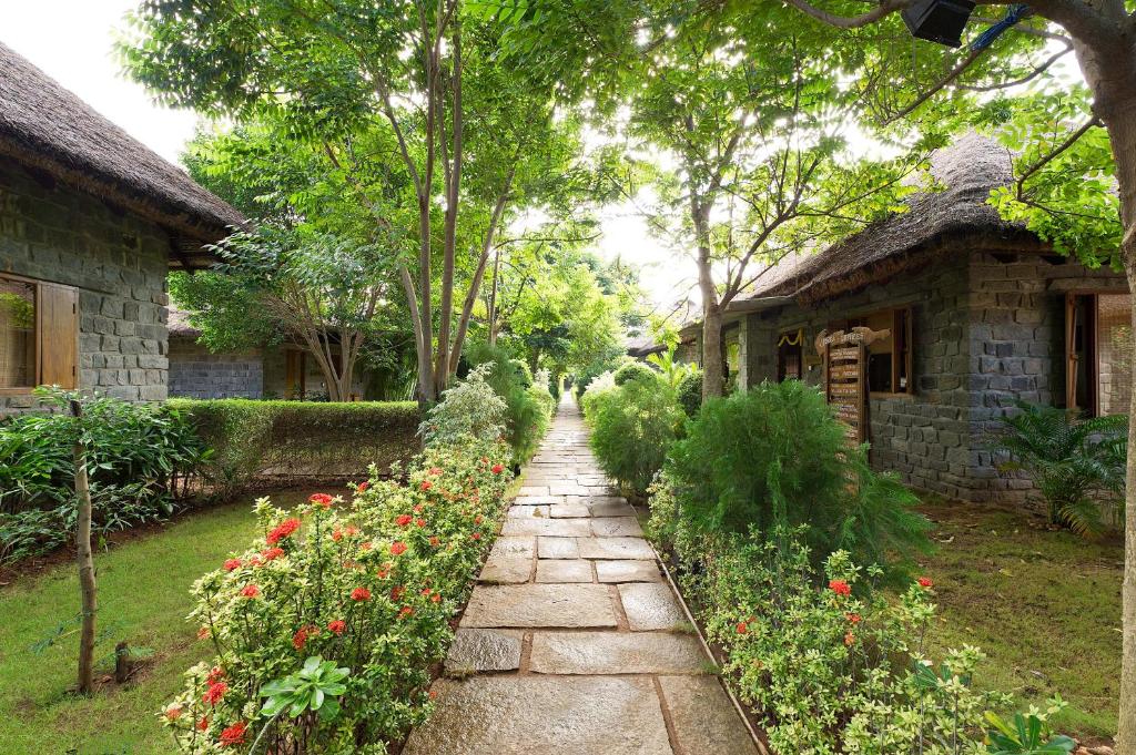 un chemin en pierre devant une maison fleurie dans l'établissement Sparsa Resort Thiruvanamalai, à Tiruvannāmalai
