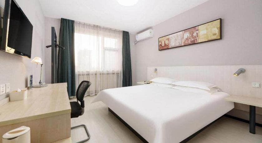 a hotel room with a large white bed and a desk at Jinjiang Inn Dalian Development Zone Jinma Road Light Railway Station in Jinzhou