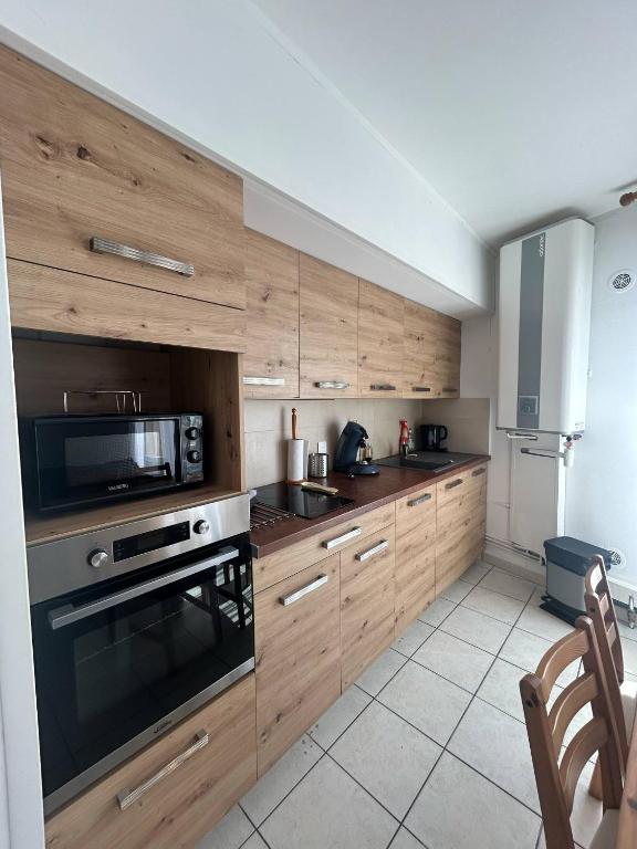 une cuisine avec des armoires en bois et une cuisinière et un micro-ondes dans l'établissement Le Marceau, à Mèze