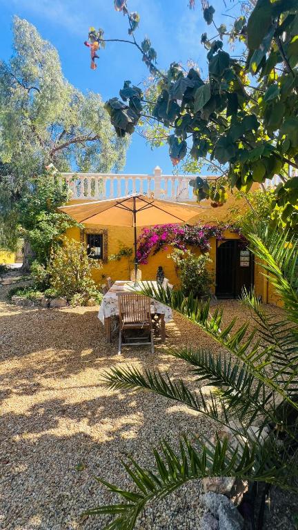 a yellow house with a table and an umbrella at Seraphina Bookings Mojacar in Mojácar